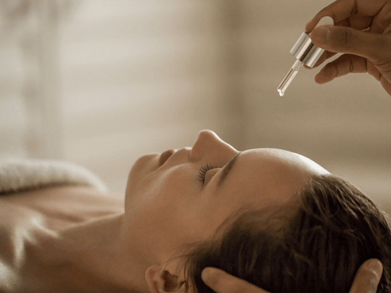 Person having moisture droplets applied to their forehead at a spa