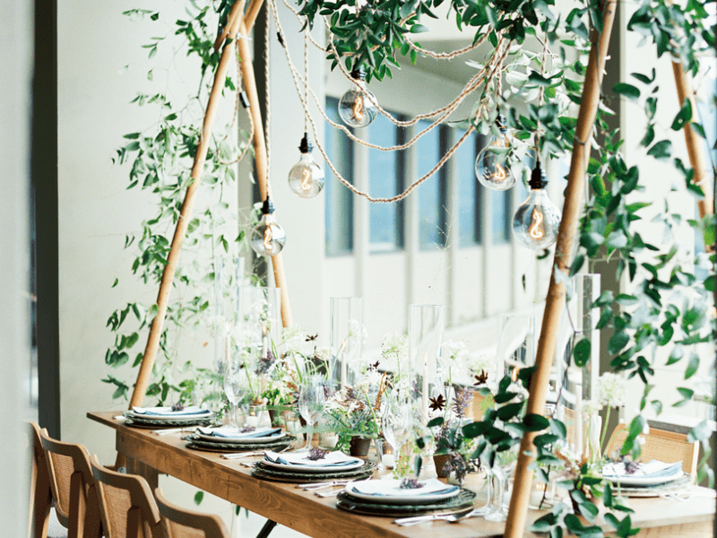 Outside dining table with overhead trellis full of greenery