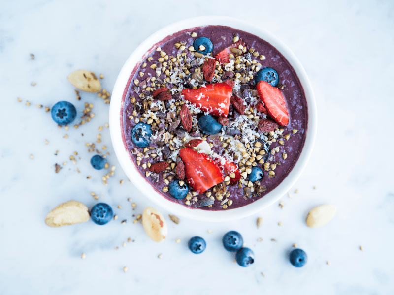 A smoothie bowl topped with strawberries, blueberries and oats
