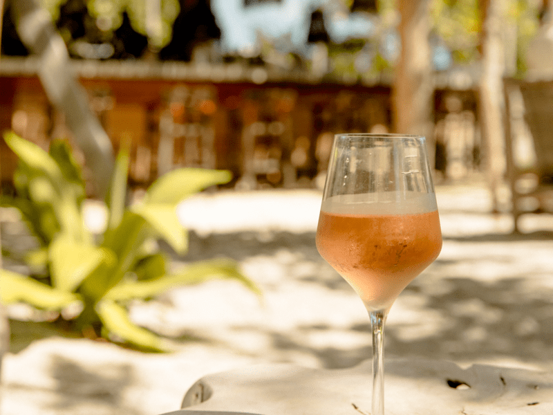 Glass of wine sitting on a sandy tree stump