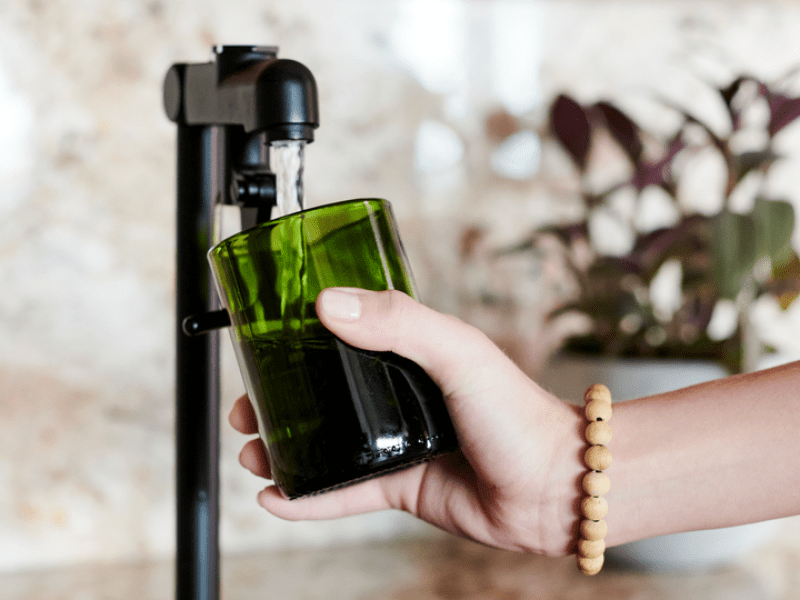 Person filling a glass of water at a tap