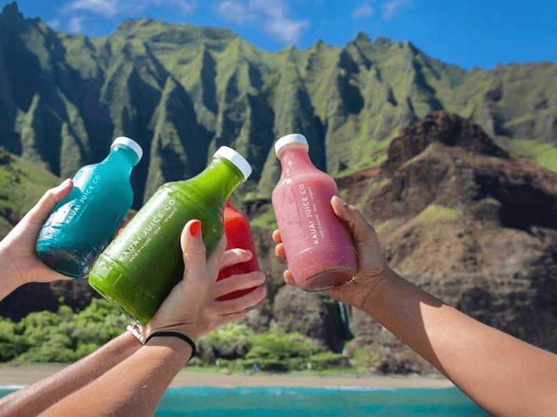 People holding bottles of Kauai juice