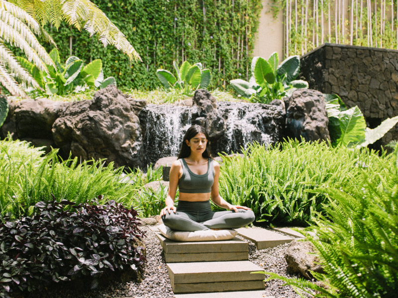 Woman Meditating surrounded by lush greenery