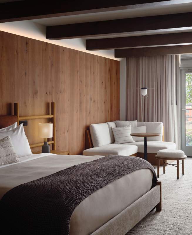 Bedroom with a large king size bed, seating area, and doors which lead out onto a patio