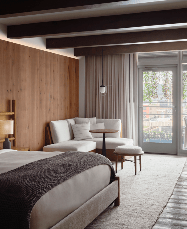Bedroom with a large king size bed, seating area, and doors which lead out onto a patio