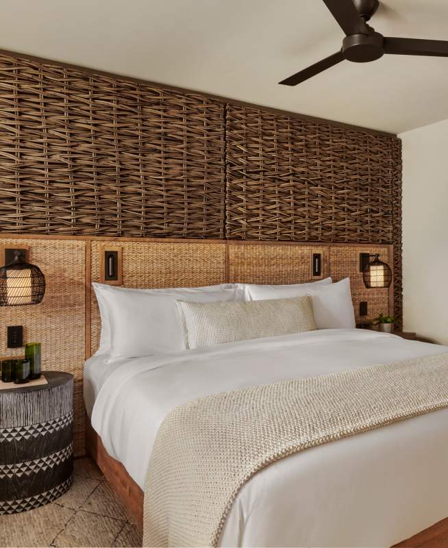 Made bed in room with wickered wall