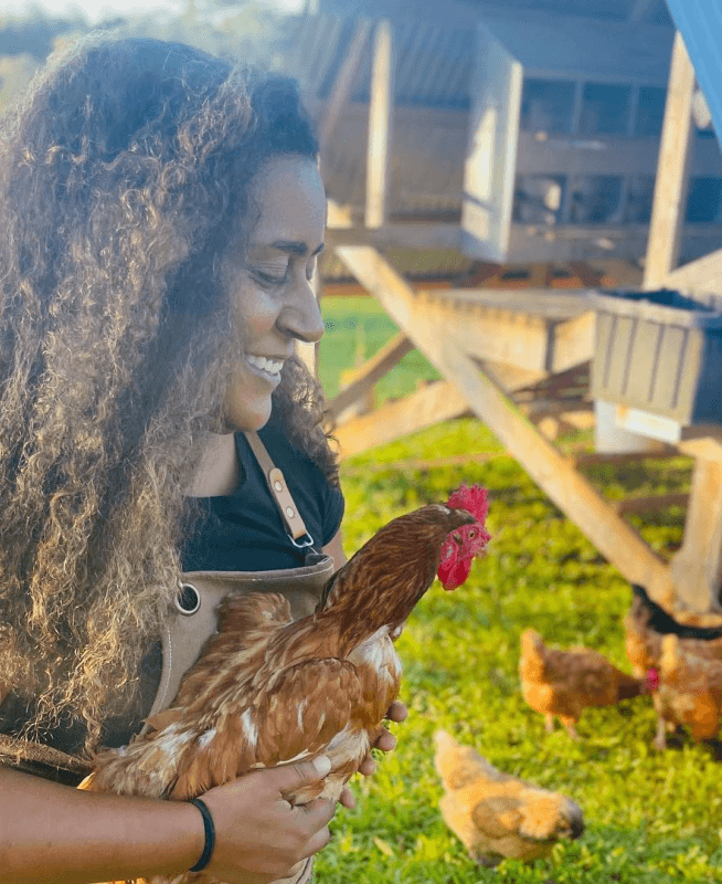 Person in overalls holding a chicken