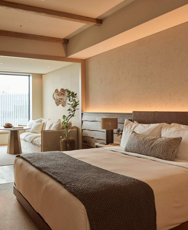 Guestroom with a King bed, lounge seat by the window looking out at the city of Tokyo