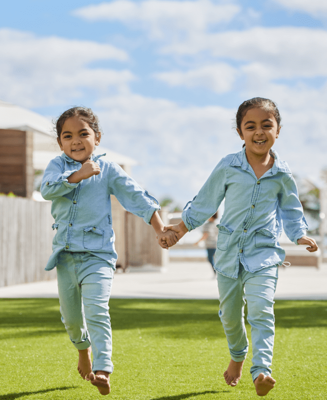 Two kids running while holding hands 
