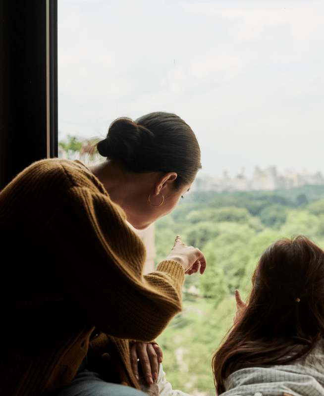 Mom and daughter overlooking Central Park from hotel room