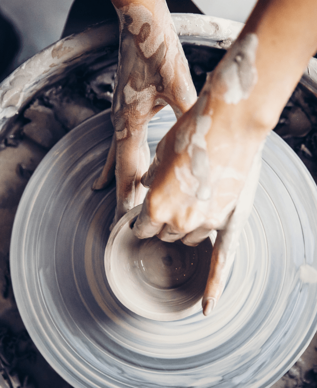 hands shaping pottery on a pottery wheel