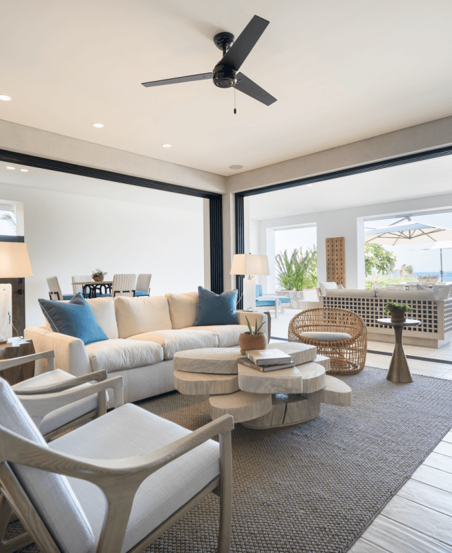 A large furnished room opens onto an outdoor patio with views of the ocean