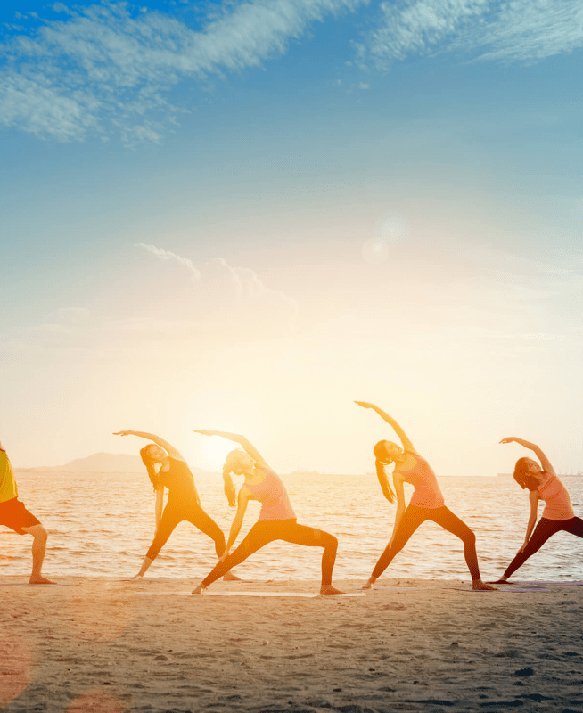 A group of people doing yoga on a beach