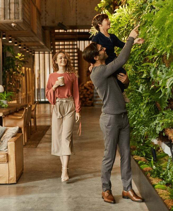 Father holding up his son to look at a living wall