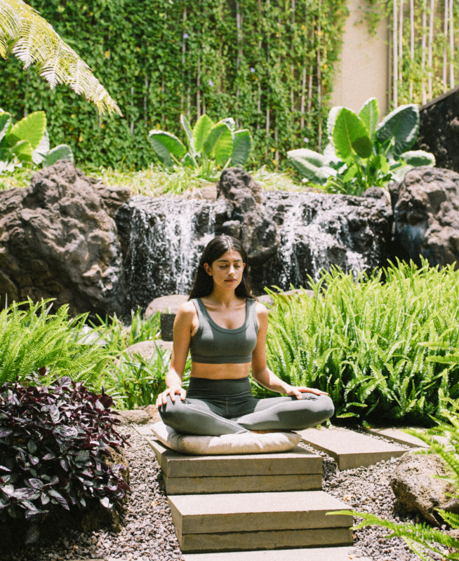 Woman Meditating surrounded by lush greenery