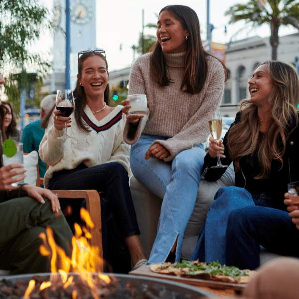 Friends gather around a firepit on the outdoor patio