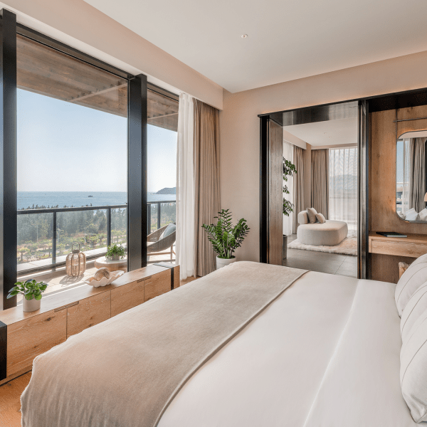 A bed facing the window which looks out to the ocean