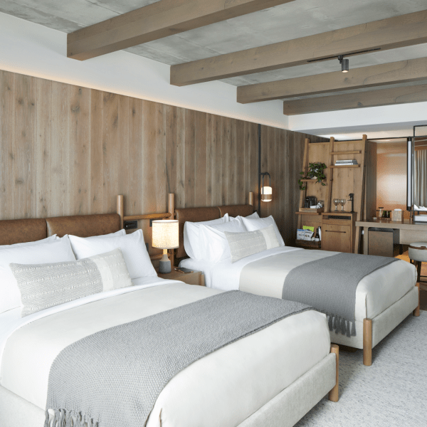 Wood paneled room with two made beds