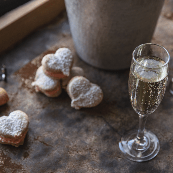 Powdered heart shaped pastries adjacent to a bottle of champagne