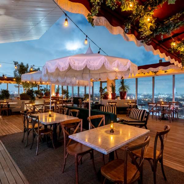 A wooden trellis wraps around the perimeter of the Harriet's rooftop restaurant at dusk. 