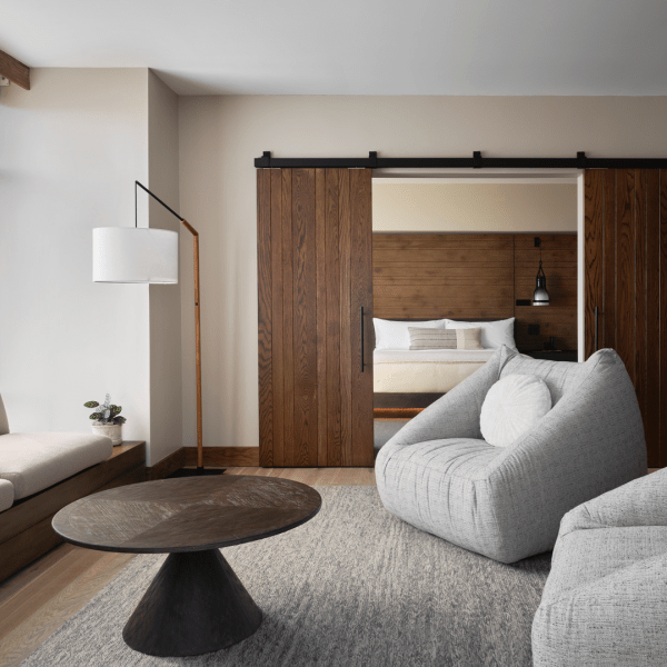 Two large gray chairs and a sofa positioned around a dark brown circular coffee table, overlooking views of the water