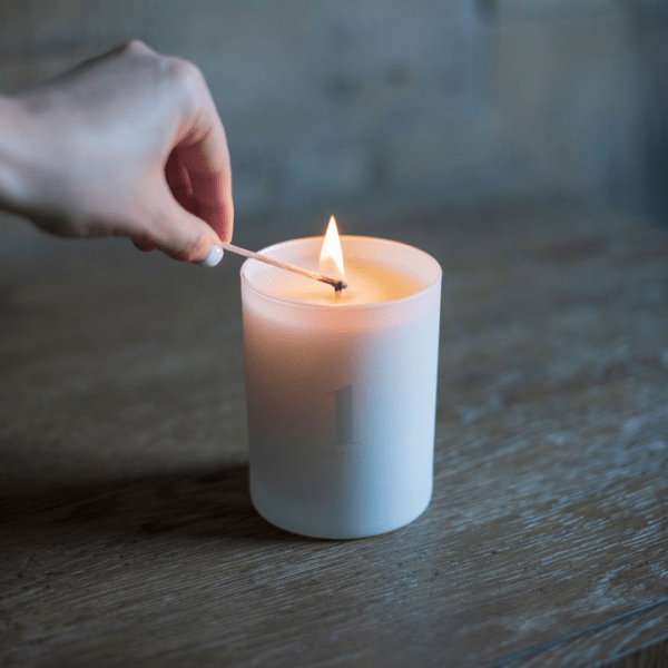 A hand lighting a candle with a match