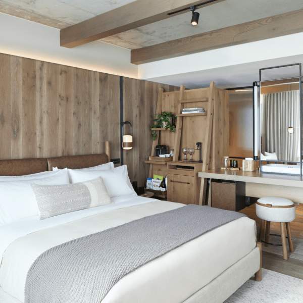 A king sized bed sits to the left of a small kitchenette area.  A vanity mirror sits atop a desk to the right of the kitchenette