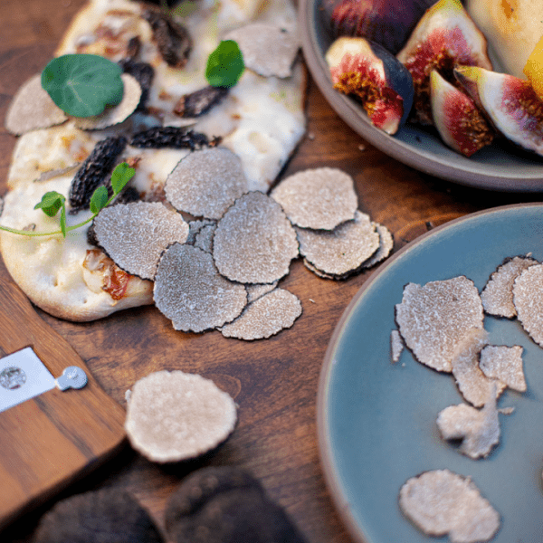 Flatbread with shaved truffle coming out of pizza oven