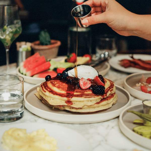 syrup being poured on stack of pancakes
