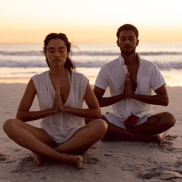 Two people meditating on a beach