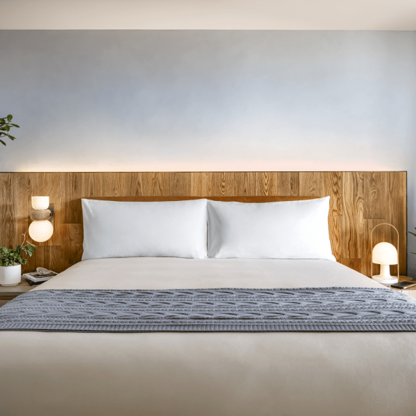 A king size bed with green potted plants on either side