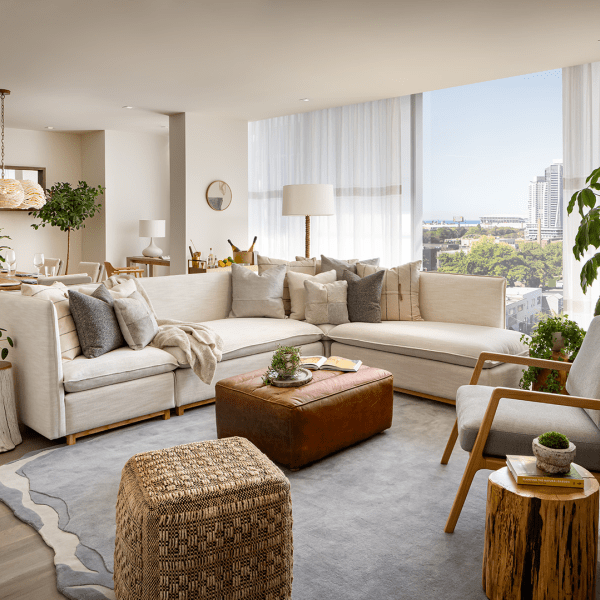 A living room area with a large white sectional sits in front of a large wooden dining room table.  