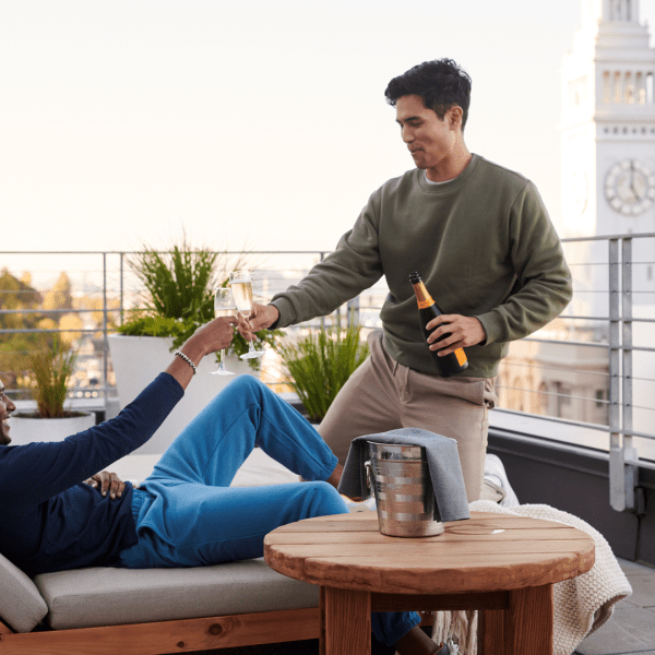 Two people sharing a glass of champagne on an outdoor patio