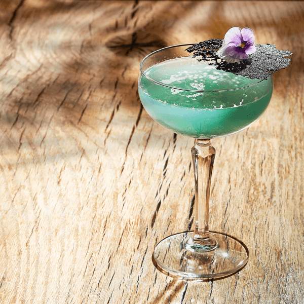Green cocktail with a flower on the rim