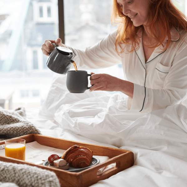 A woman in bed pouring coffee