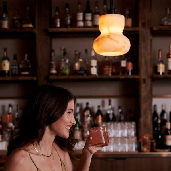 Person smiling with a drink in hand at the 1 Hotel West Hollywood lobby bar