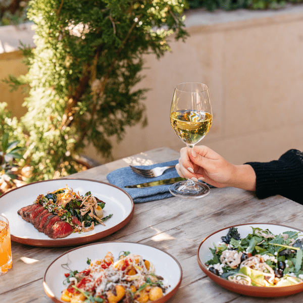 hand holding a glass of wine outside with food