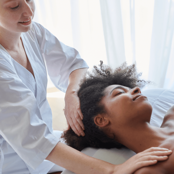 A woman receives a shoulder massage as she lies face up on a massage table