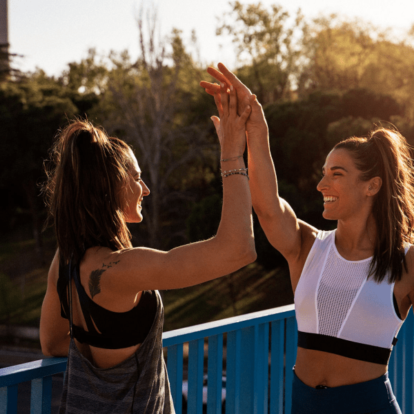 Two people high fiving outside - on running