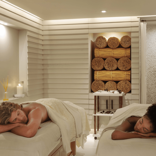 A couple, one man and one woman, lay face down on massage beds, relaxed