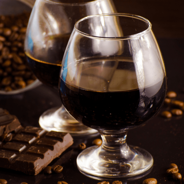 A glass of rum, a broken chocolate bar and cacao beans