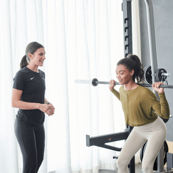 Personal trainer working with someone doing a squat