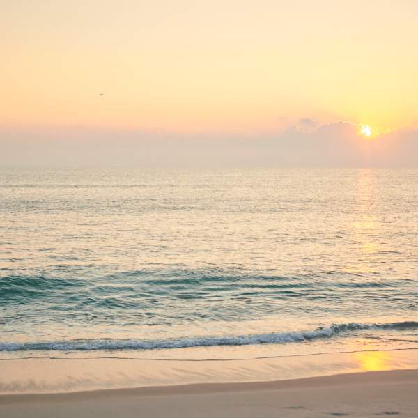 Ondas a rebentar numa praia ao pôr do sol
