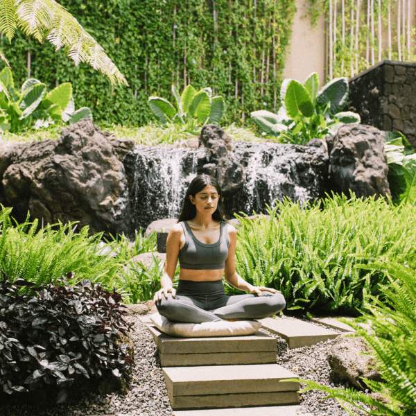 Woman Meditating surrounded by lush greenery