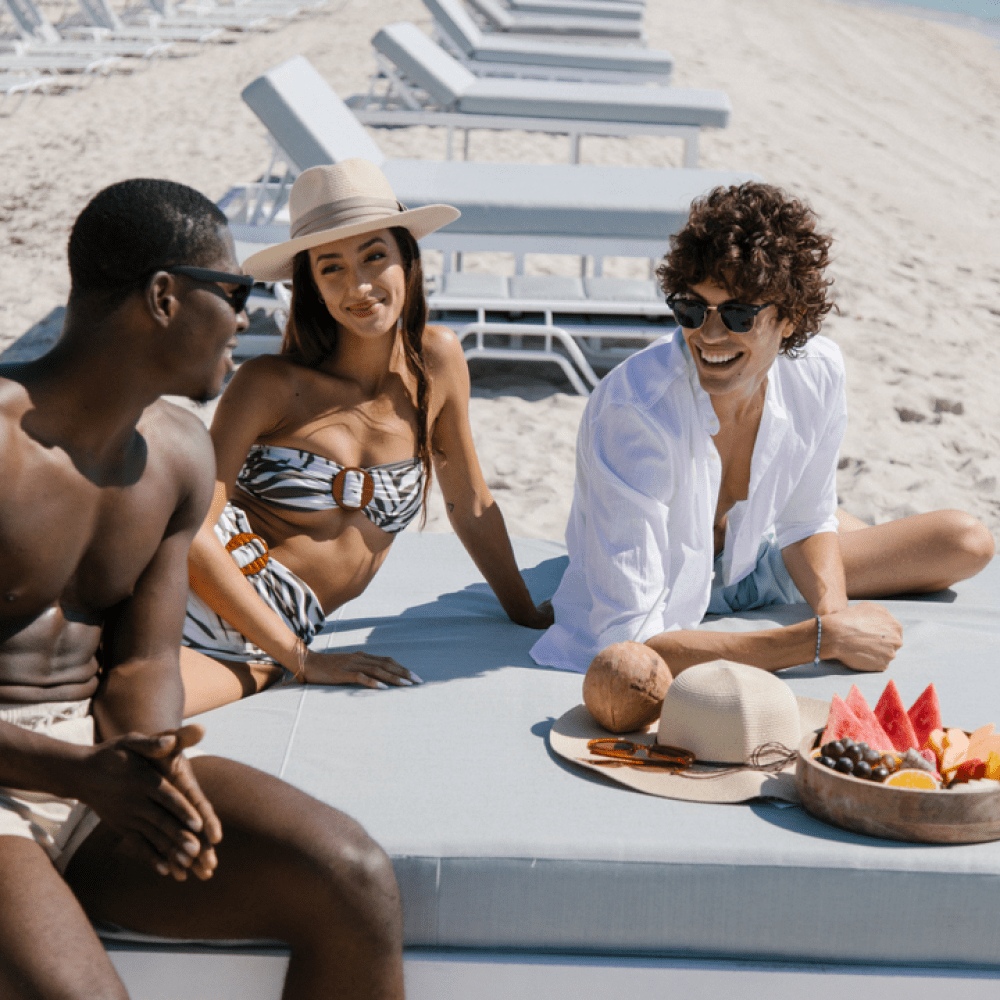 Three people relaxing on a beach chair with some fruit