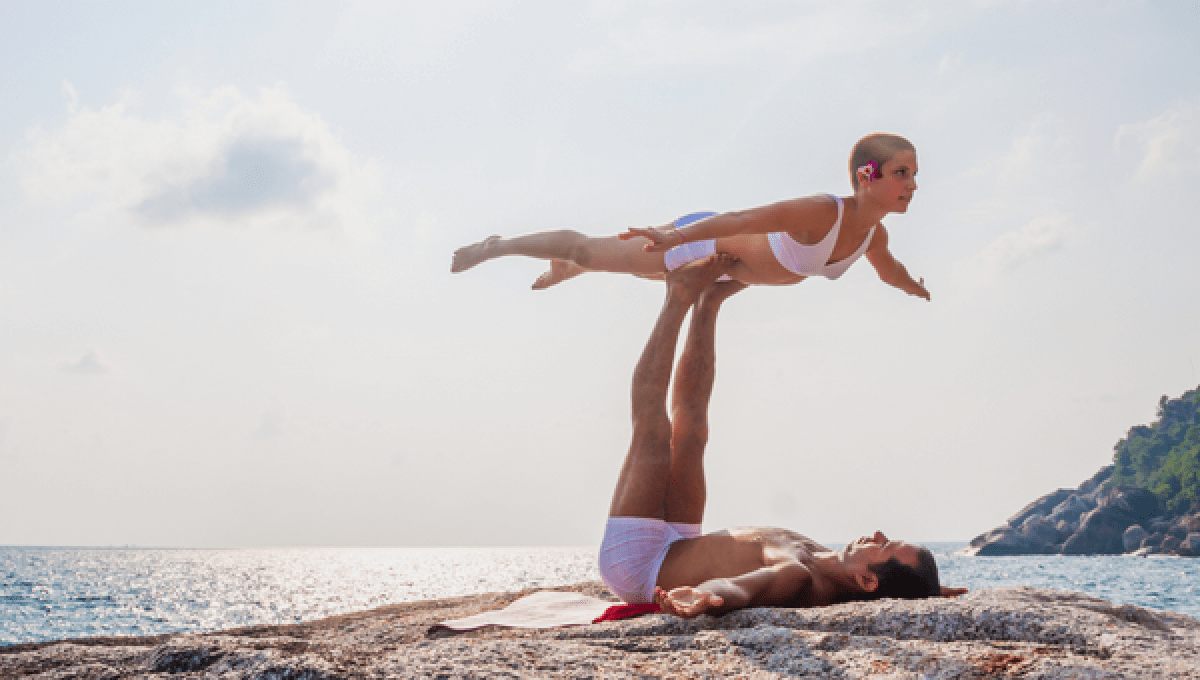 Two people doing acrobatic yoga on the beach