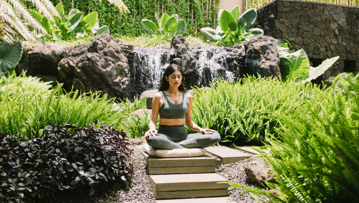 Woman Meditating surrounded by lush greenery