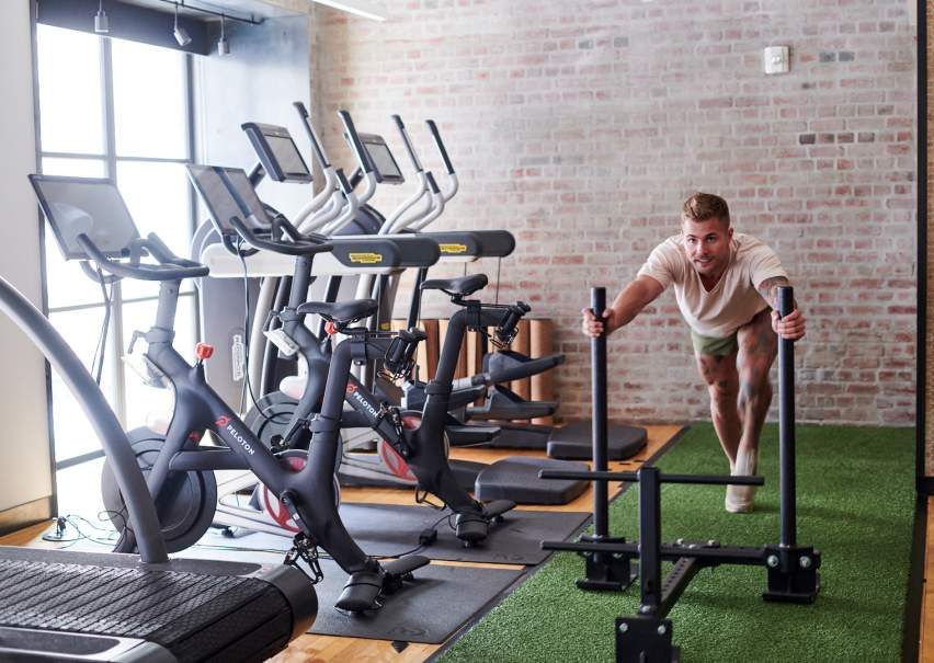 Gym with treadmills and man pushing weights on turf