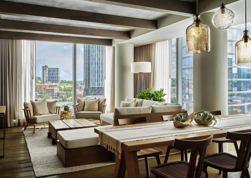 1 Hotels Nashville penthouse suite with a dining room table and living room furniture overlooking views of the city