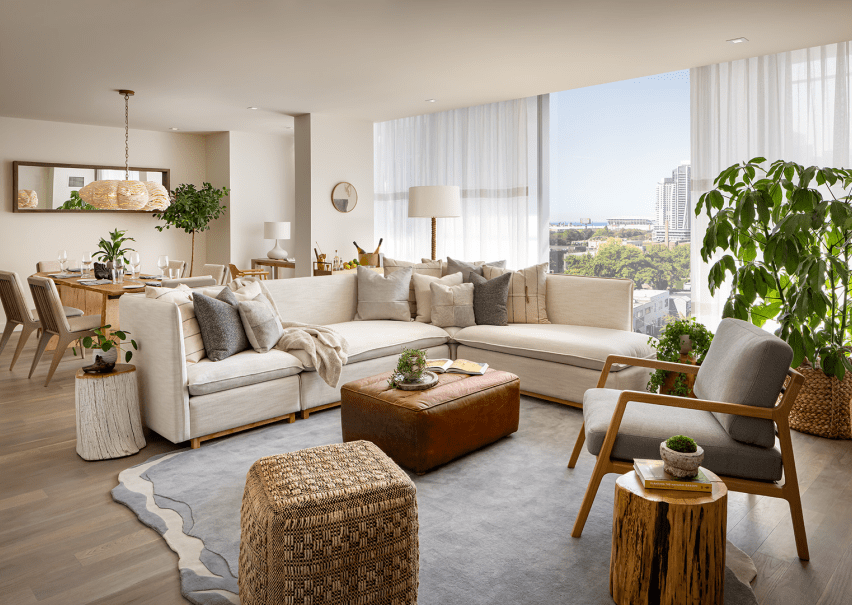 A living room area with a large white sectional sits in front of a large wooden dining room table.  